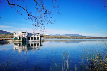 Lake Banyoles with the historic bathhouse reflected in still blue water
