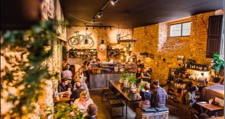 Cyclists filling the warm stone interior of La Fabrica cafe in Girona